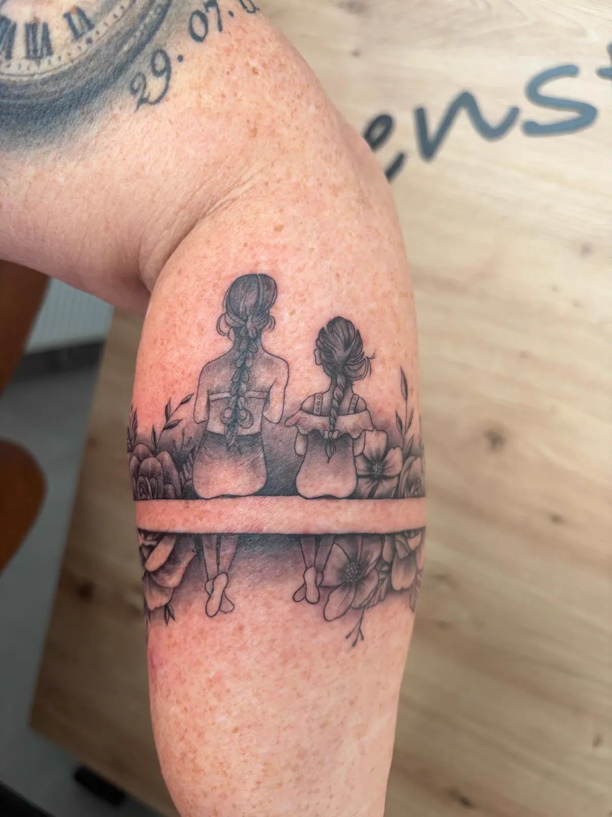 Feines Armband-Tattoo mit Mutter und Tochter zwischen Blumen — Han, Alpenstich