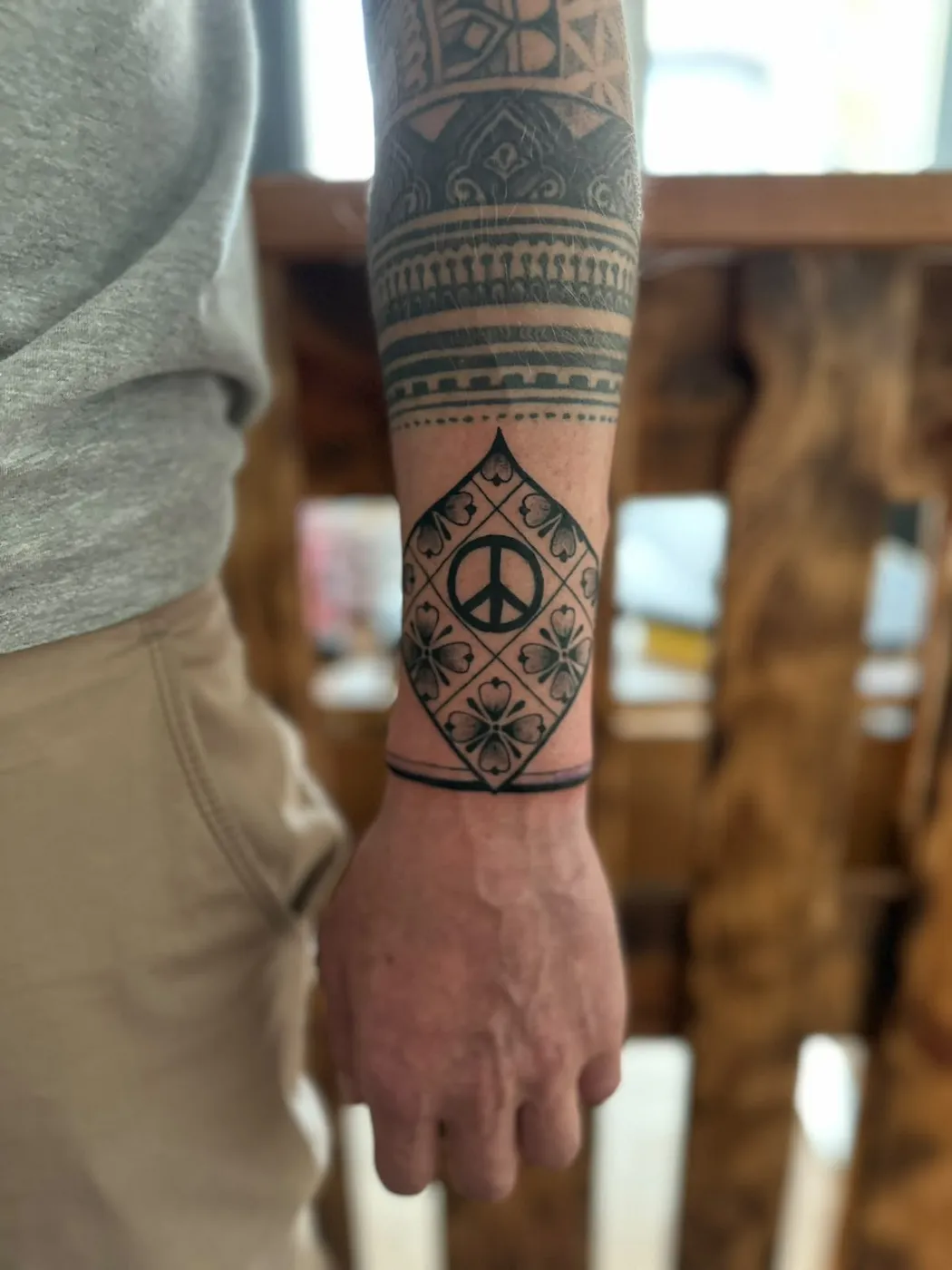 Maori-Ornament-Armband mit Peace-Zeichen am Unterarm — Tschenky, Alpenstich