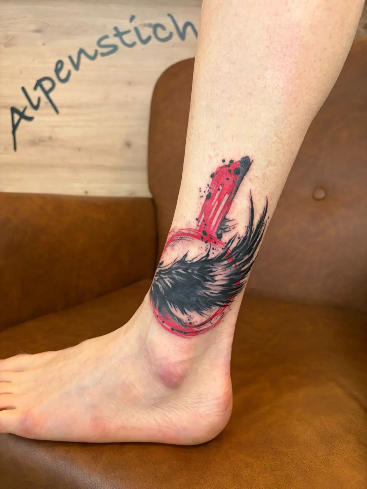Trash-Polka-Tattoo mit Feder und Dolch am Knöchel in Rot-Schwarz — Han, Alpenstich