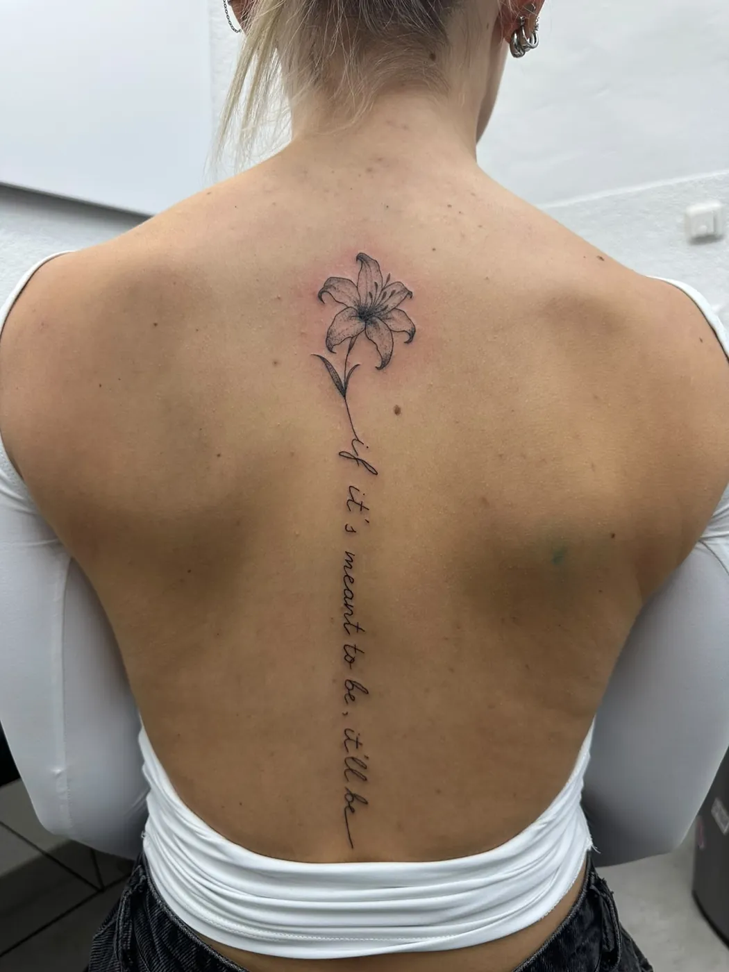 Fineline-Lilie mit Schriftzug entlang der Wirbelsäule — Tschenky, Alpenstich